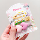 Pack of four hair clips on a card. Two clips are daisy-themed, and two are heart-themed.