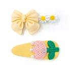 Three hair clips: yellow bow, daisy clip, and yellow clip with pink and green embellishments.
