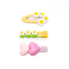 Three hair clips with daisy and heart designs.
