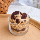 Candle in a glass jar with creamy texture and chocolate elements on a woven surface