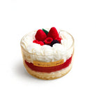 Dessert with whipped cream and berries in a glass container on a white background