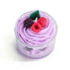 Candle shaped like a cupcake with purple frosting, berries, and a glass container on a white background