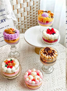 Assorted small desserts in glass bowls on a textured surface with a wicker chair in the background.
