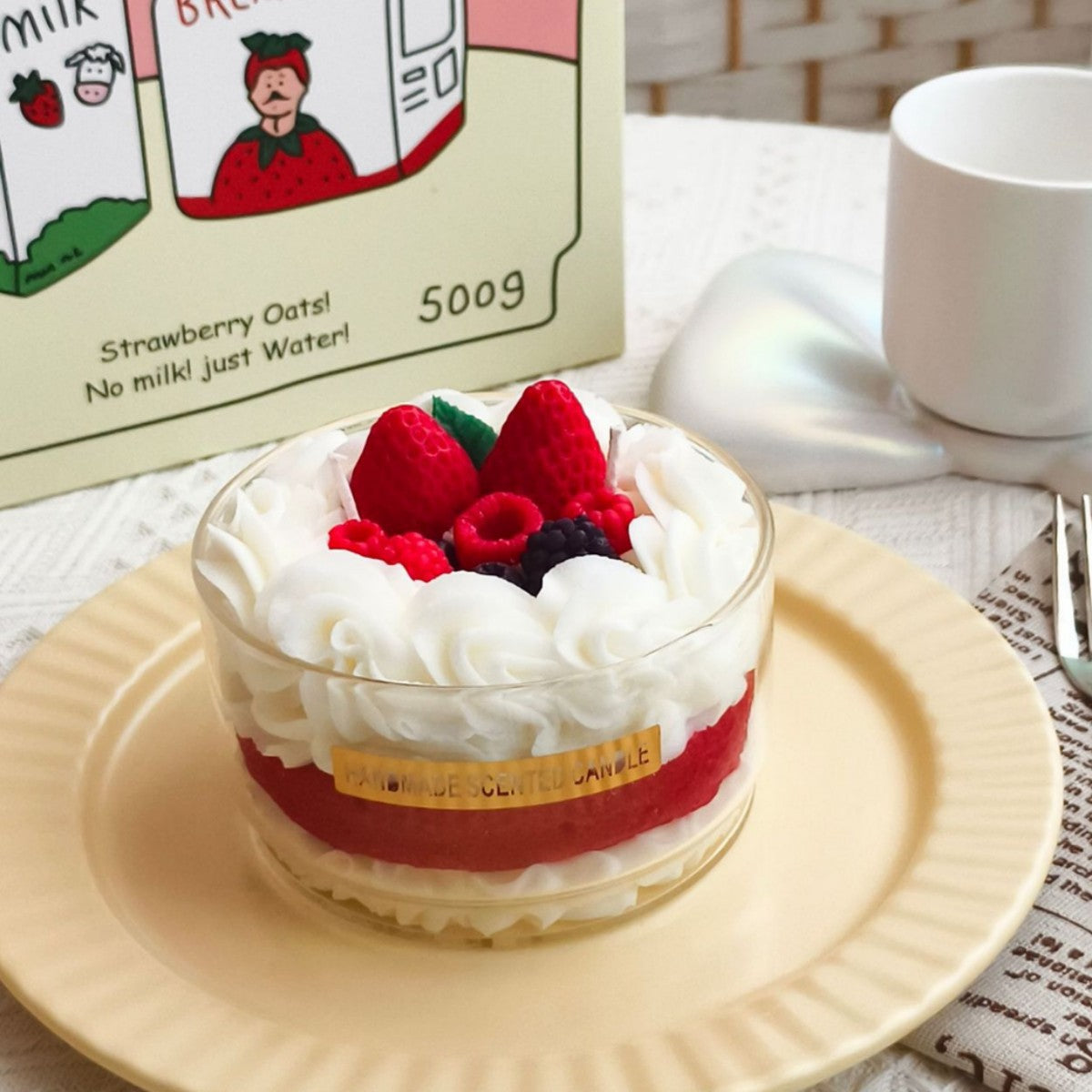 Small dessert with berries on a plate next to a carton of strawberry oat milk.