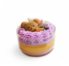 Handmade scented candle with a teddy bear design on top, featuring purple and yellow layers.