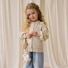 Soft white plush duck keychain with bow, by Snuggle Bunnies, hanging from gold bag, worn by child in cream cardigan and jeans, lifestyle front view