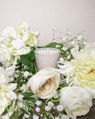 Decorative arrangement of white flowers with a candle on a light background